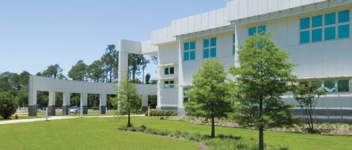 Modern college campus building at Pensacola State College with greenery and trees.