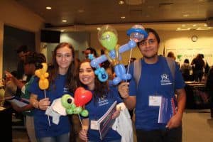 Student Government Association students holding balloon animals and flyers at college event.