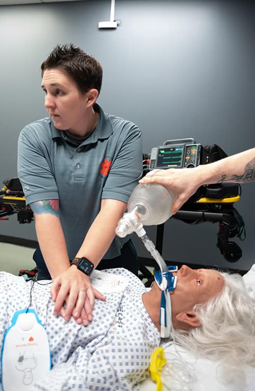 Emergency medical technician practicing airway management on patient mannequin.