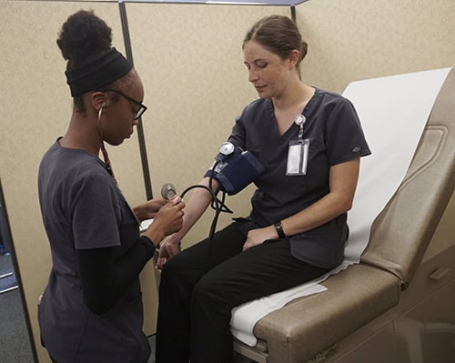 Medical assisting student measuring blood pressure for clinical skills training.