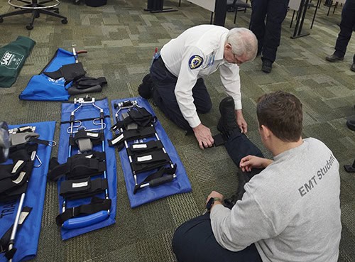 Emergency Medical Technician student practicing first aid techniques with instructor.