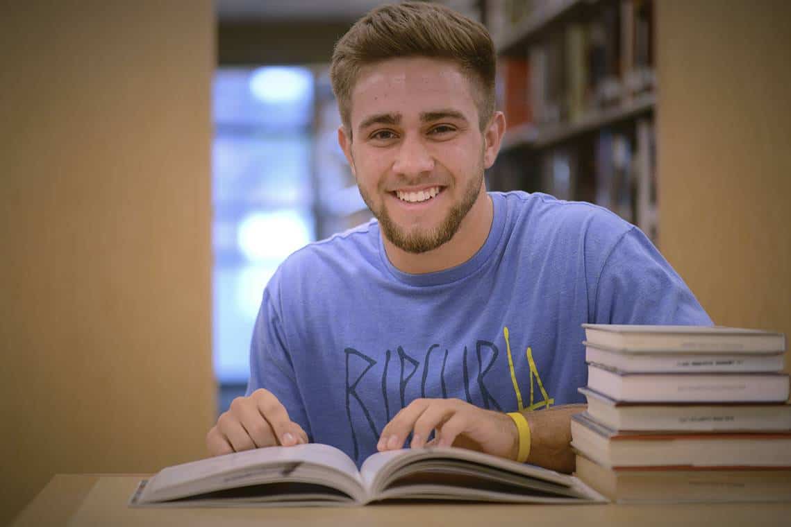 Student studying accounting technology at Pensacola State College in a library setting.