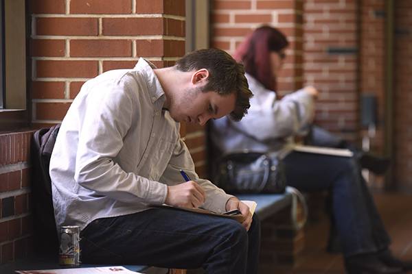 Business management student taking notes in college classroom.