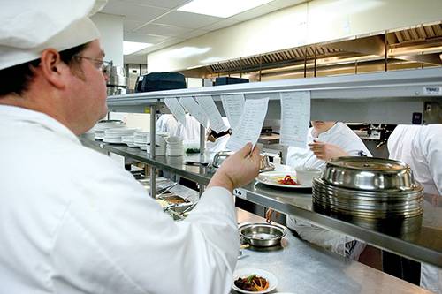 Culinary arts student reviewing recipes in a commercial kitchen environment.