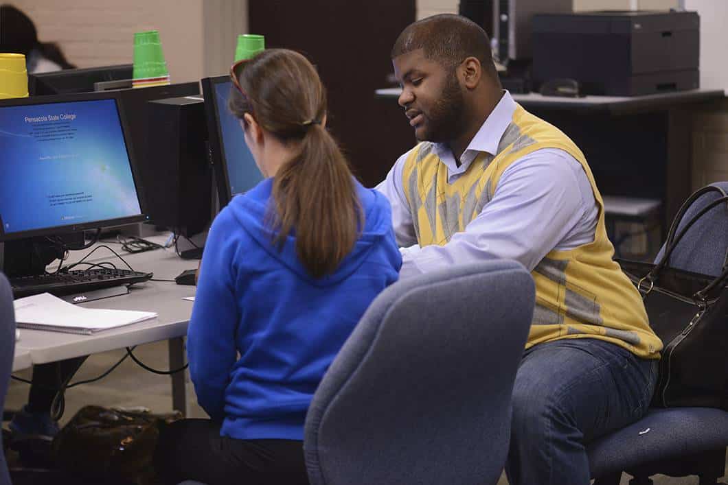 Computer Information Technology student consulting with instructor in classroom setting.