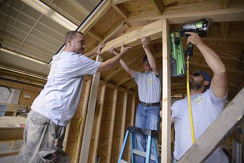 High school carpentry students working on a wooden frame in a classroom setting.