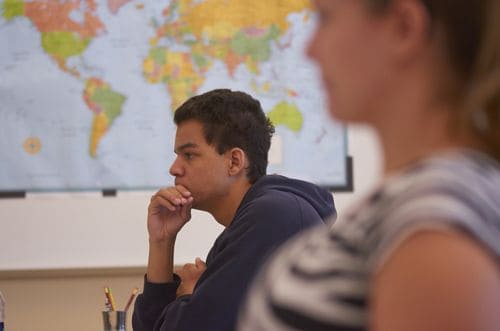 Engaged students in a history classroom with a world map, promoting higher education and global awar.