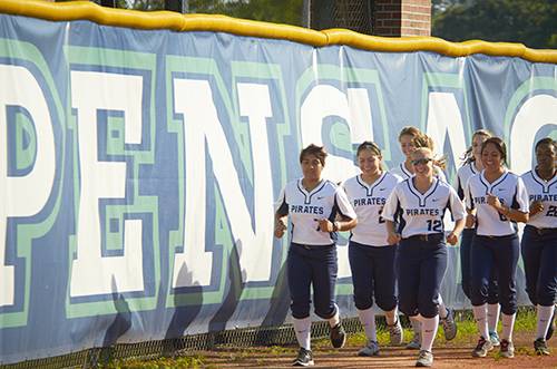 Students in sports science program running on the field near the Pensacola State College sign.