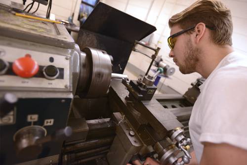 CNC machinist operating industrial lathe for metal fabrication and manufacturing training at Pensaco.
