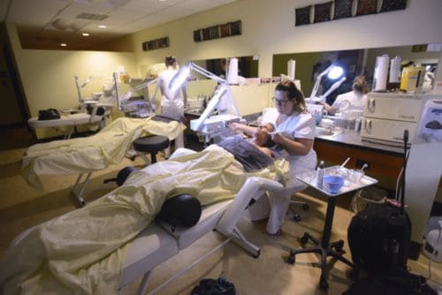 Highly skilled students practicing advanced facial treatments in a professional cosmetology lab.