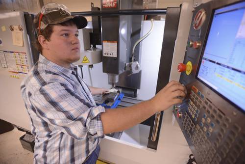CNC composite fabricator and programmer working with industrial machinery.