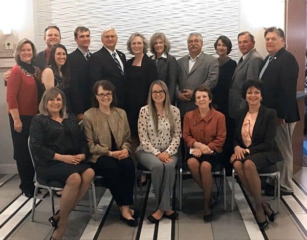 Group of professionals in formal attire gathered in a conference room at Pensacola State College for.