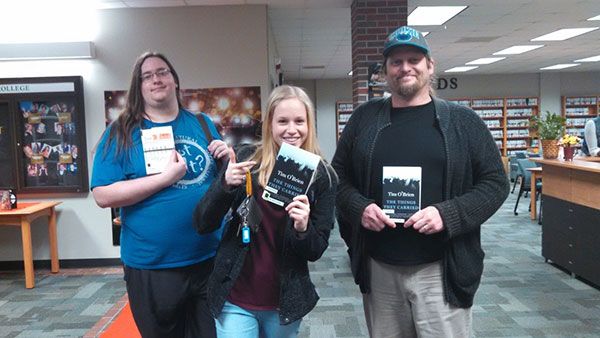Students holding books and a drink in a college library setting.