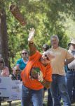 Lumberjack tossing log during outdoor event with spectators and greenery.