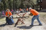 Lumberjack competition with students and instructors showcasing traditional woodcutting skills.