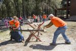 Lumberjack competition featuring two participants sawing a log with an audience watching.