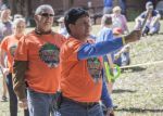Axe throwing activity at a lumberjack festival with participants and spectators outdoors.