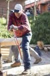Lumberjack using a saw outdoors at Pensacola State College, demonstrating skills in forestry and out.