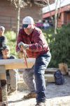 Lumberjack demonstrating woodcutting skills during outdoor college activity.