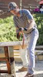 Lumberjack student cutting wood with a handsaw outdoors on campus.