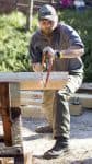 Lumberjack student using a handsaw to cut wood during a practical skills class at Pensacola State Co.