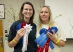 Highly motivated students holding award ribbons at graduation ceremony.