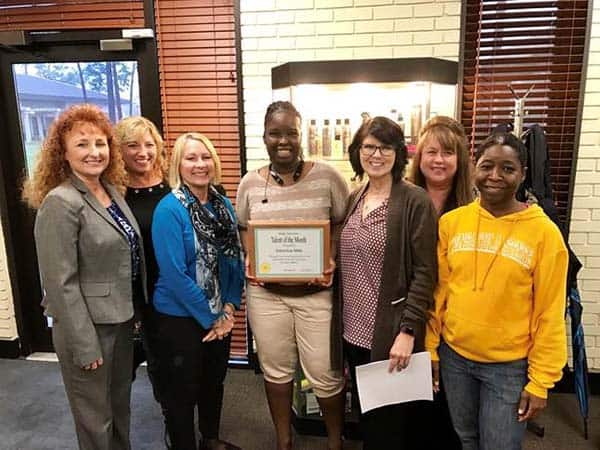 Diverse group of women celebrating academic achievement, with one holding a certificate of recogniti.
