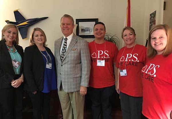 College staff and students at Pensacola State College event, smiling and posing for photo.
