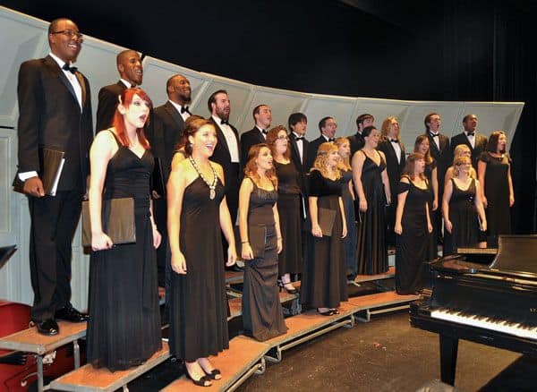 Choral and jazz students sing in a college auditorium for community engagement.