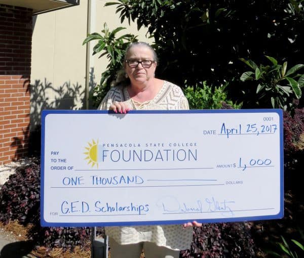 GED instructor holding large check for $1,000 donation to PSC Foundation.
