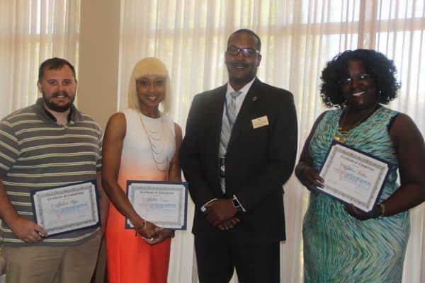 Group of diverse veterans holding certificates at graduation ceremony for Veterans Upward Bound prog.