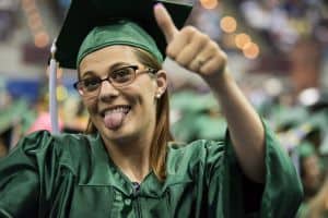 Happy graduate in cap and gown celebrating academic achievement.