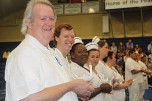 Diverse students and faculty celebrating educational achievements in a college gymnasium.