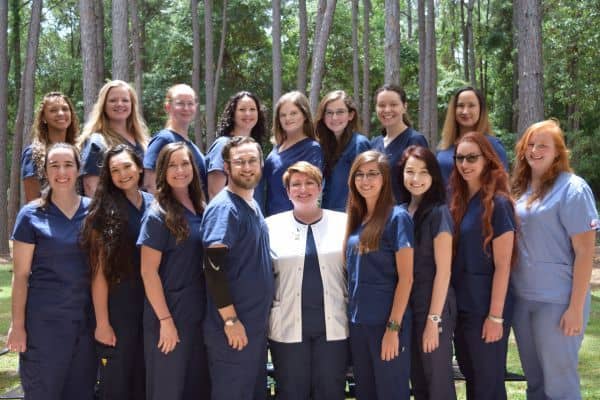 Dedicated veterinary technology students celebrating graduation outdoors.