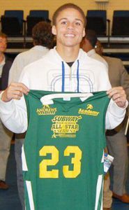 Young male basketball athlete holding green and yellow team jersey at Pensacola State College.