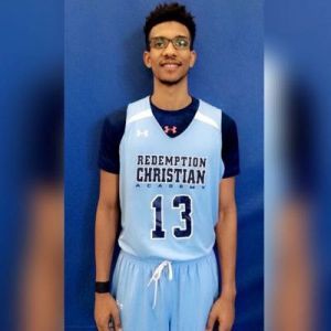 Basketball player in blue uniform at Pensacola State College gymnasium.