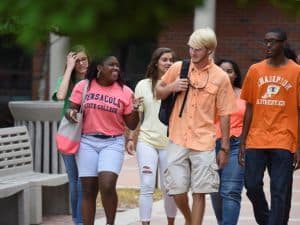 Students walking and talking on a college campus during fall semester.