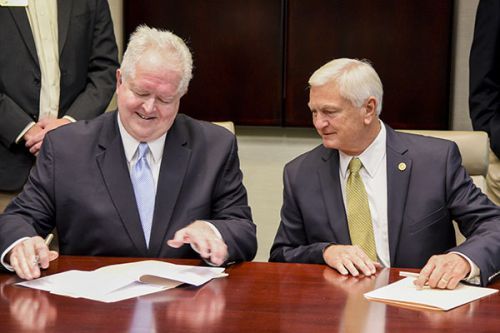 Higher education officials signing an agreement at a formal event, showcasing collaboration and acad.
