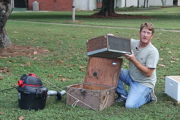 Student repairing electronic equipment outdoors on college campus.