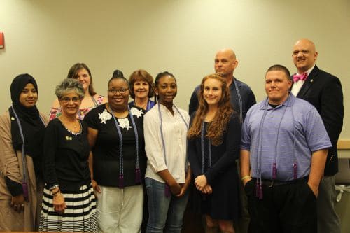 Diverse group of students and instructors smiling in classroom setting.
