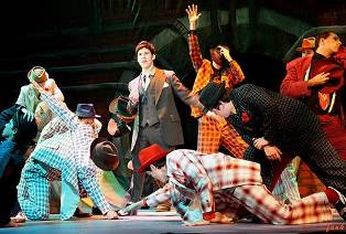 Ensemble of diverse performers in colorful costumes during a theatrical performance at Pensacola Sta.