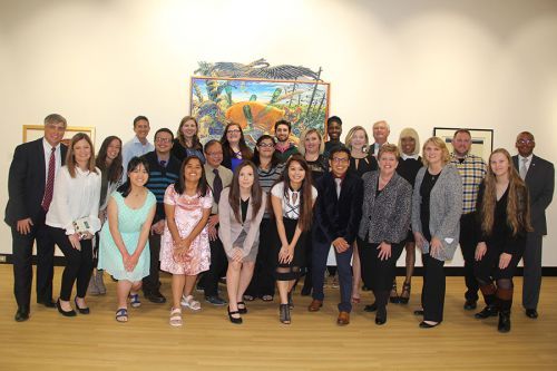 Diverse group of students and faculty gathered at Pensacola State College art exhibit in front of co.