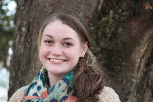 Student smiling outdoors near a tree, representing higher education at Pensacola State College.