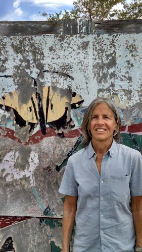 Woman smiling outdoors against urban graffiti art at Pensacola State College campus.