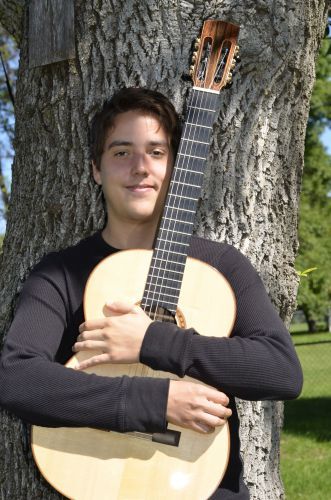 Young guitarist Xavier Jara with classical guitar, celebrating musical talent at Pensacola State Col.