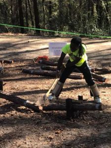 Student performing wood chopping at forestry and lumberjack competition event.