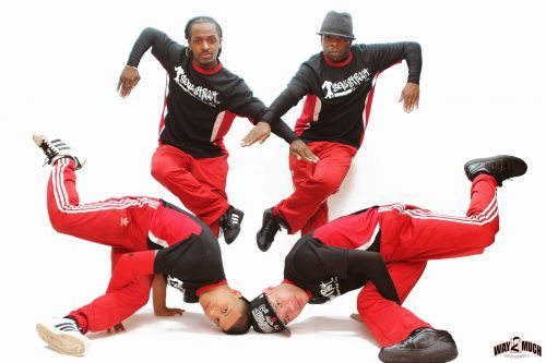 High school dance team performing dynamic acrobatic routine on stage with coordinated poses.