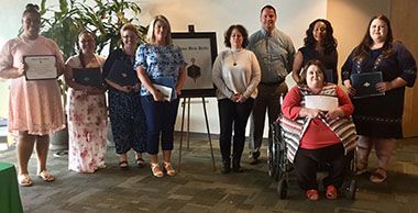 Diverse group of students, including a woman in a wheelchair, celebrating educational success at Pen.