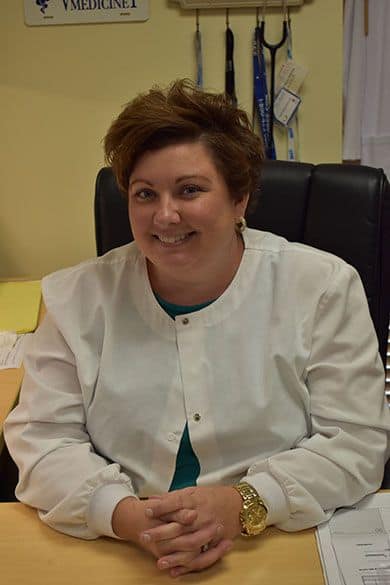Healthcare professional woman smiling in medical office setting.