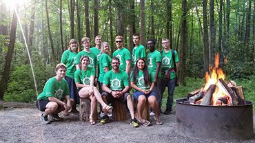 Outdoor team-building activity at Pensacola State College with students around a campfire.